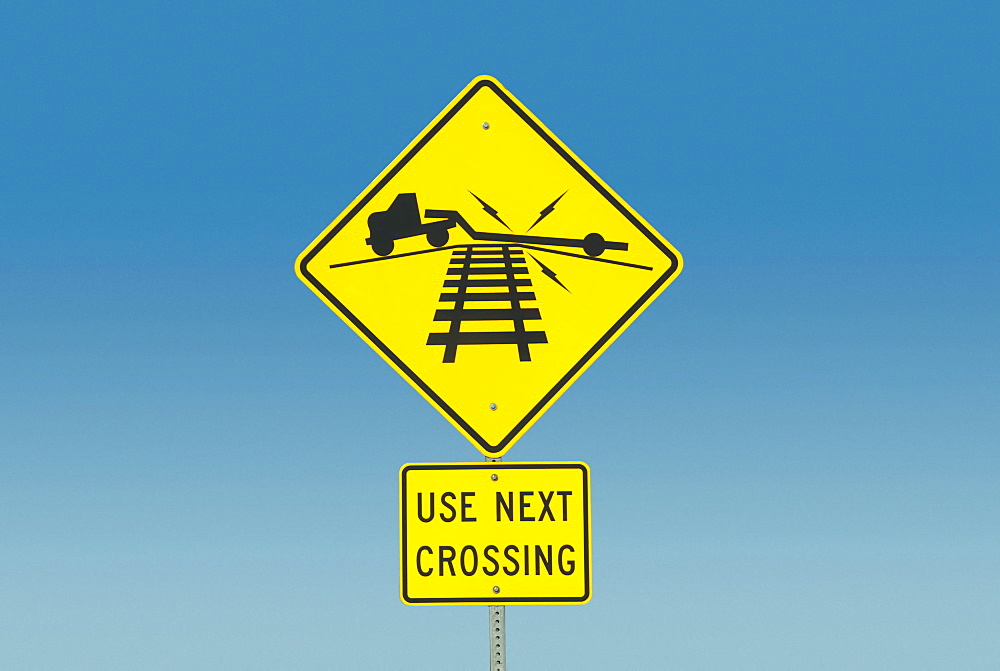 Yellow road sign depicting truck on railroad crossing