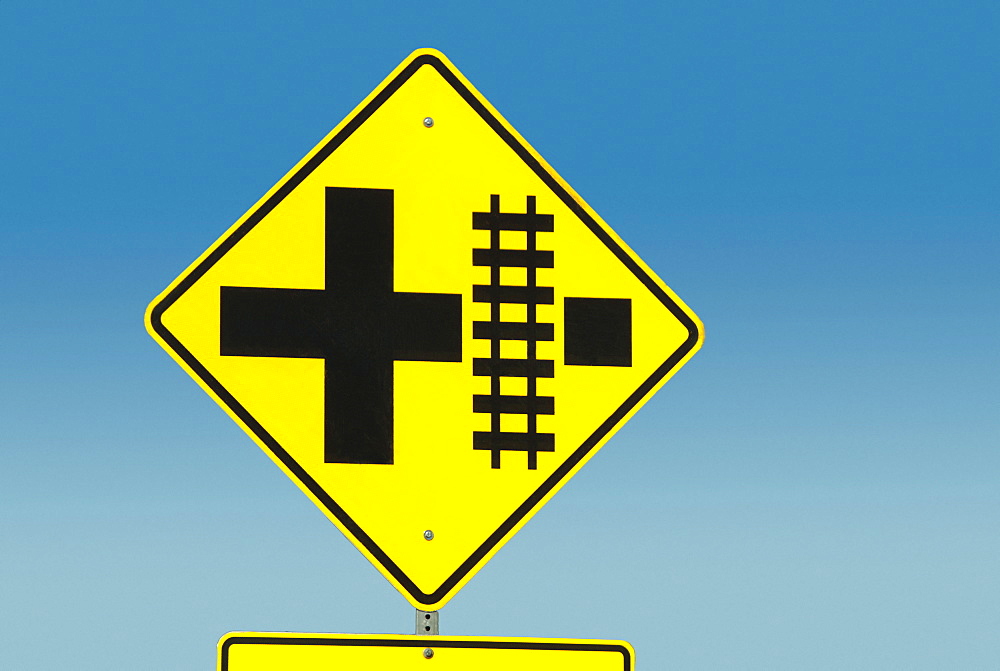 Yellow road sign depicting railroad crossing