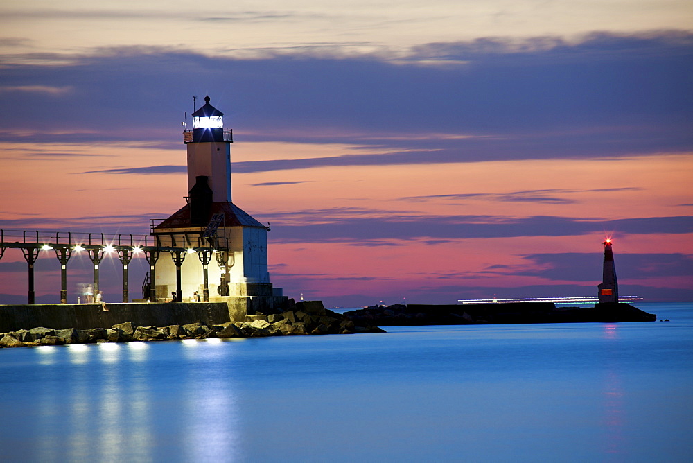 Michigan City Lighthouse at sunset. Chicago skyscrapers seen far in the background.