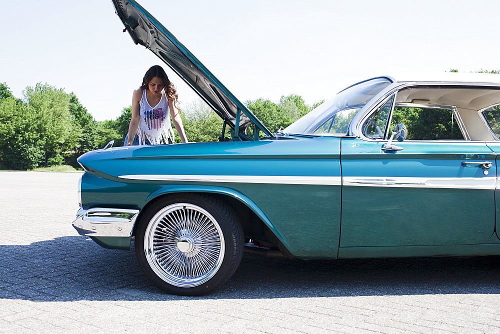 Woman standing near broken vintage car, Netherlands, Tilburg