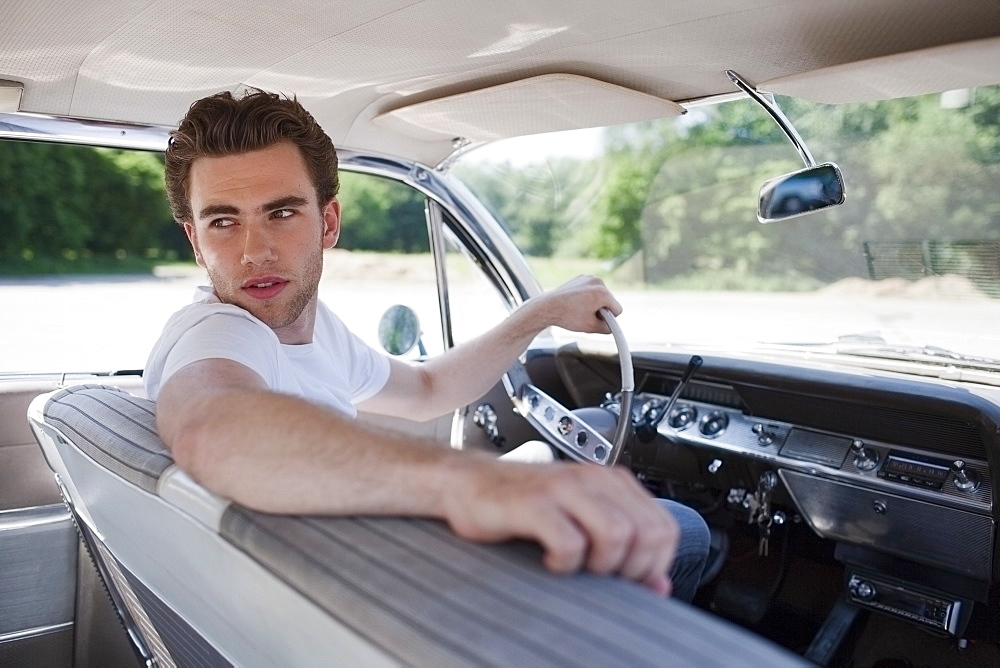 Young man in vintage car, Netherlands, Tilburg
