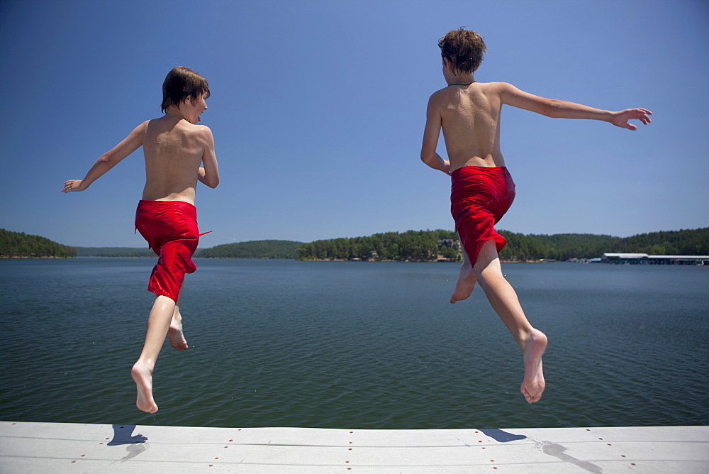 USA, Arkansas, Murfreesboro, Two brothers (8-9, 12-13) jumping into water, USA, Arkansas, Murfreesboro