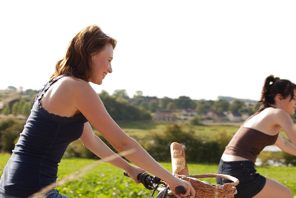 France, Picardie, Albert, Young women on bikes on country road, France, Picardie, Albert