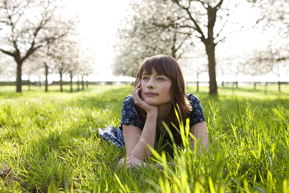 Belgium, Sint-Truiden, Portrait of young woman in spring orchard, Belgium, Sint-Truiden