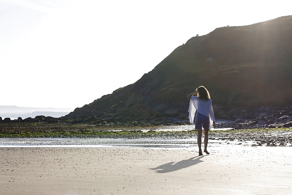 France, Pas-de-Calais, Escalles, Young woman strolling on empty beach, France, Pas-de-Calais, Escalles