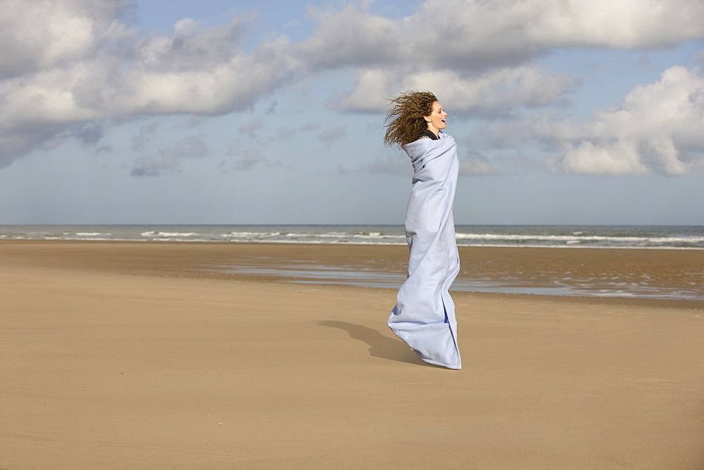 France, Pas-de-Calais, Escalles, Young woman strolling on empty beach, France, Pas-de-Calais, Escalles