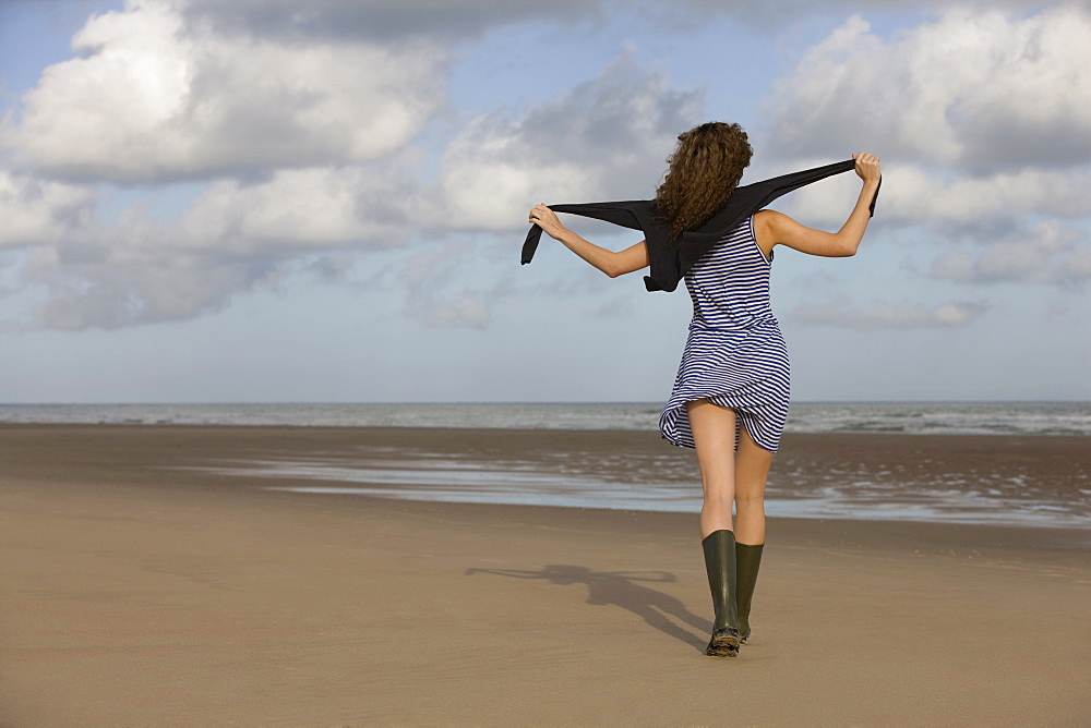 France, Pas-de-Calais, Escalles, Young woman strolling on empty beach, France, Pas-de-Calais, Escalles