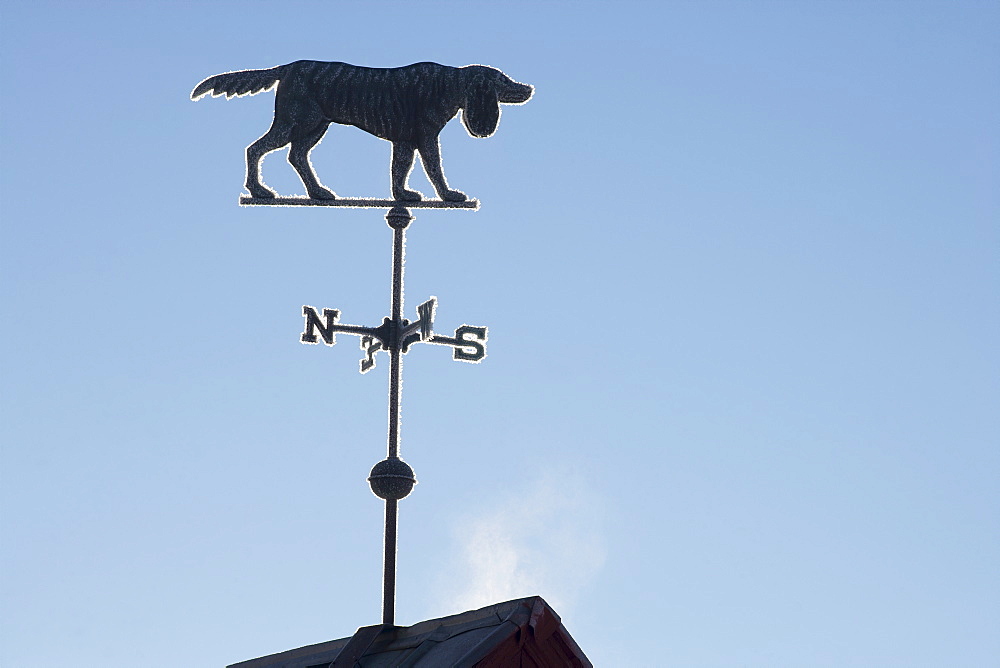 Old weather vane against blue sky