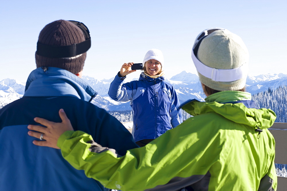 USA, Montana, Whitefish, Woman photographing friends in mountain resort