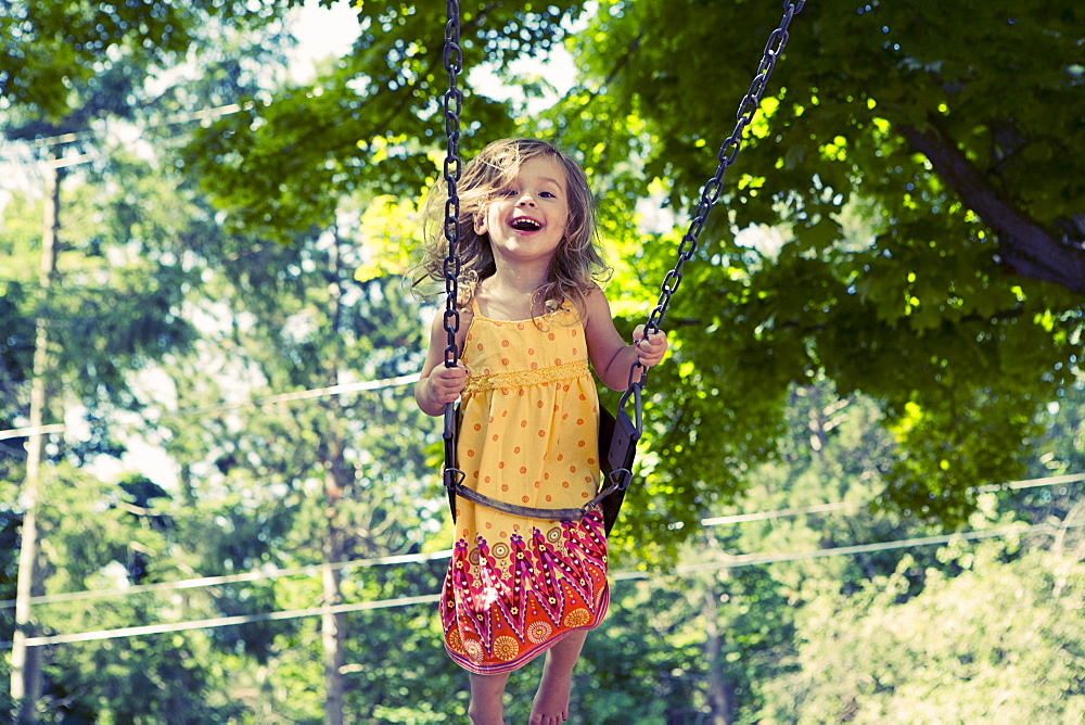 Girl (2-3) on swing in playground