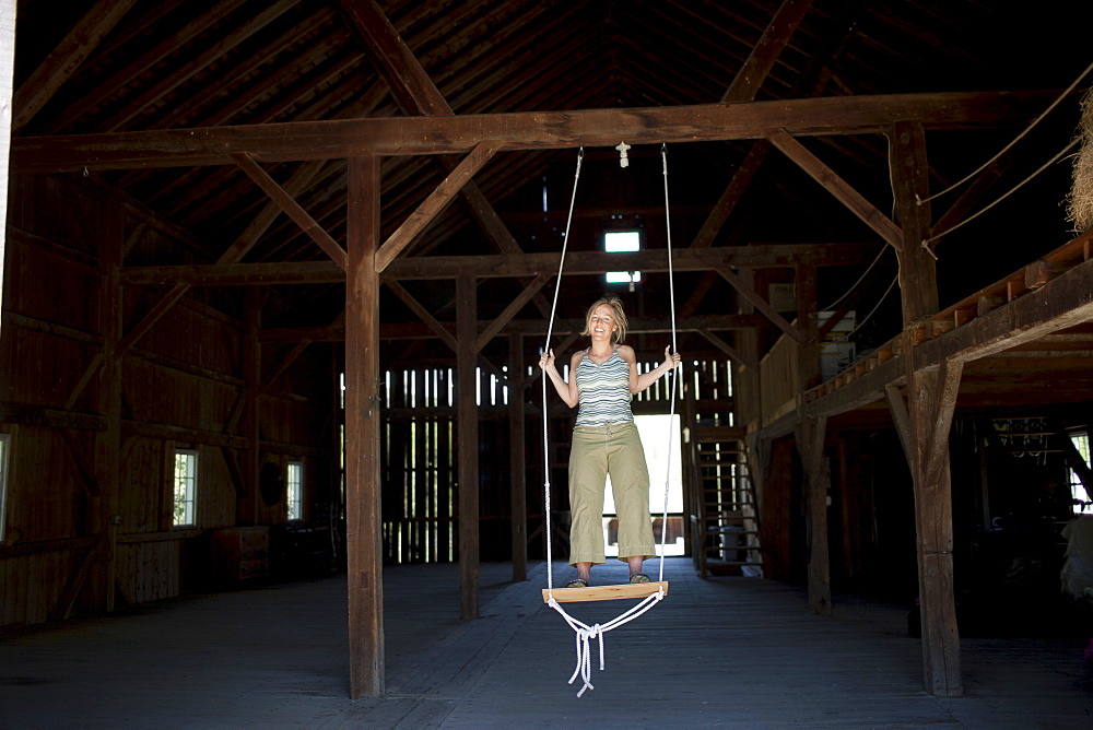 USA, Vermont, Dorset, Woman on swing in barn