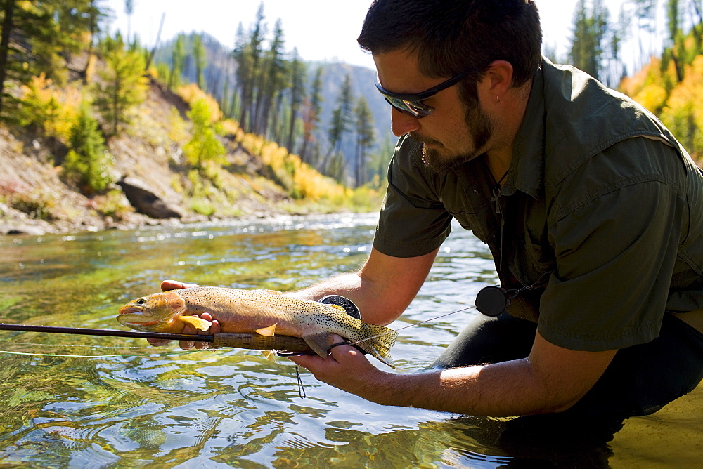 USA, Montana, Man holding fish in North Fork of Blackfoot River