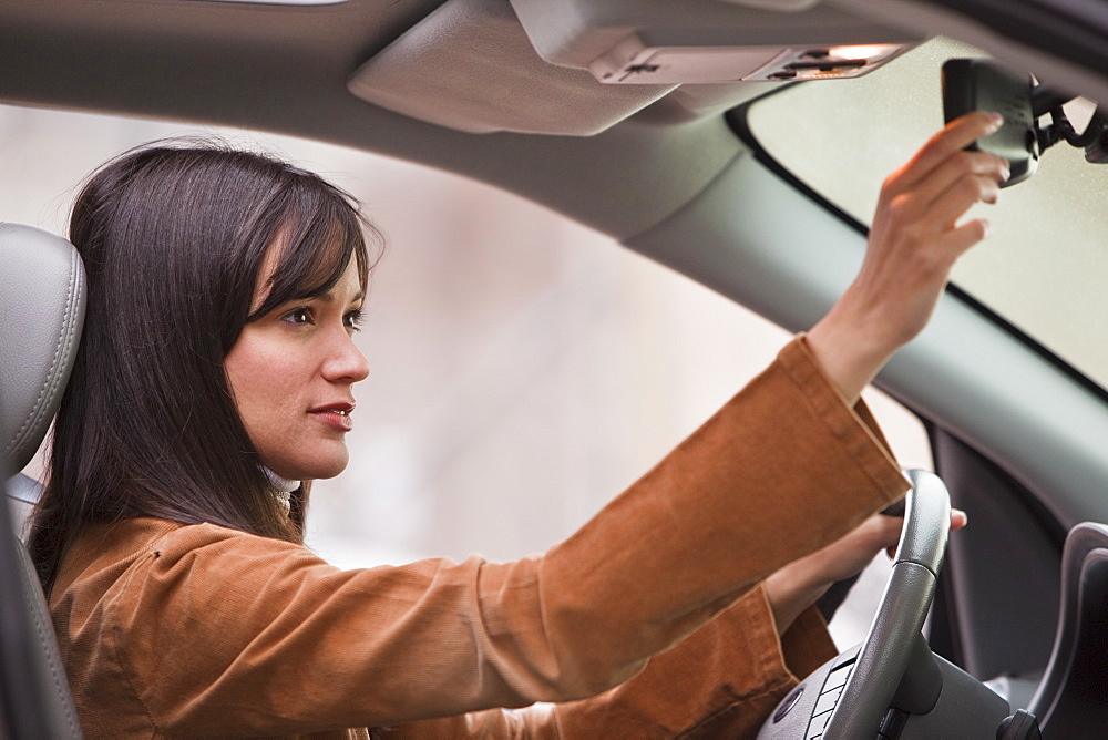 Woman adjusting rear view mirror