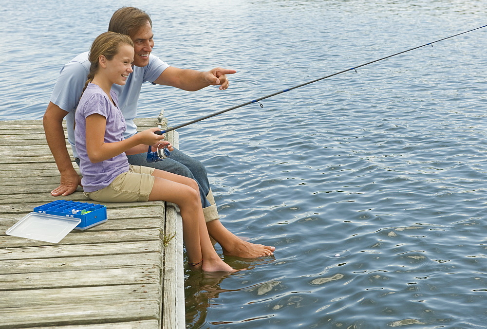 Father and daughter fishing off dock