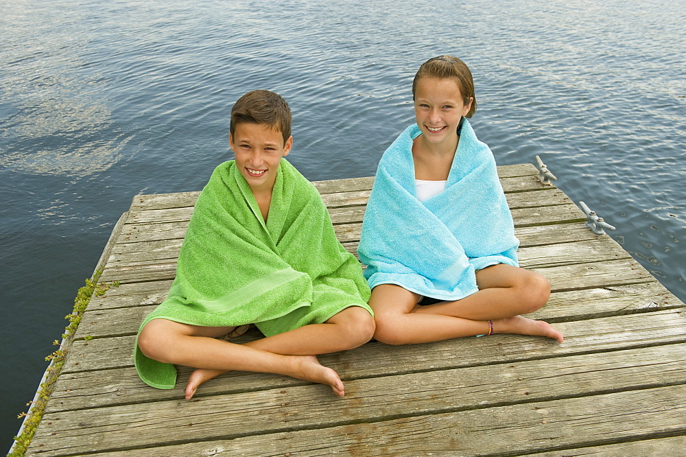 Children wrapped in towels on dock