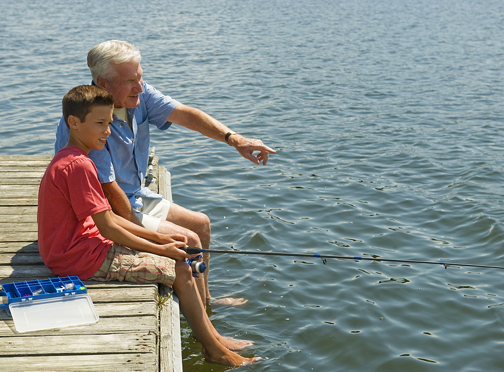 Grandfather and grandson fishing off dock