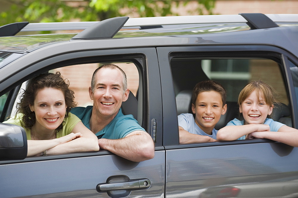 Family with two children looking out car windows