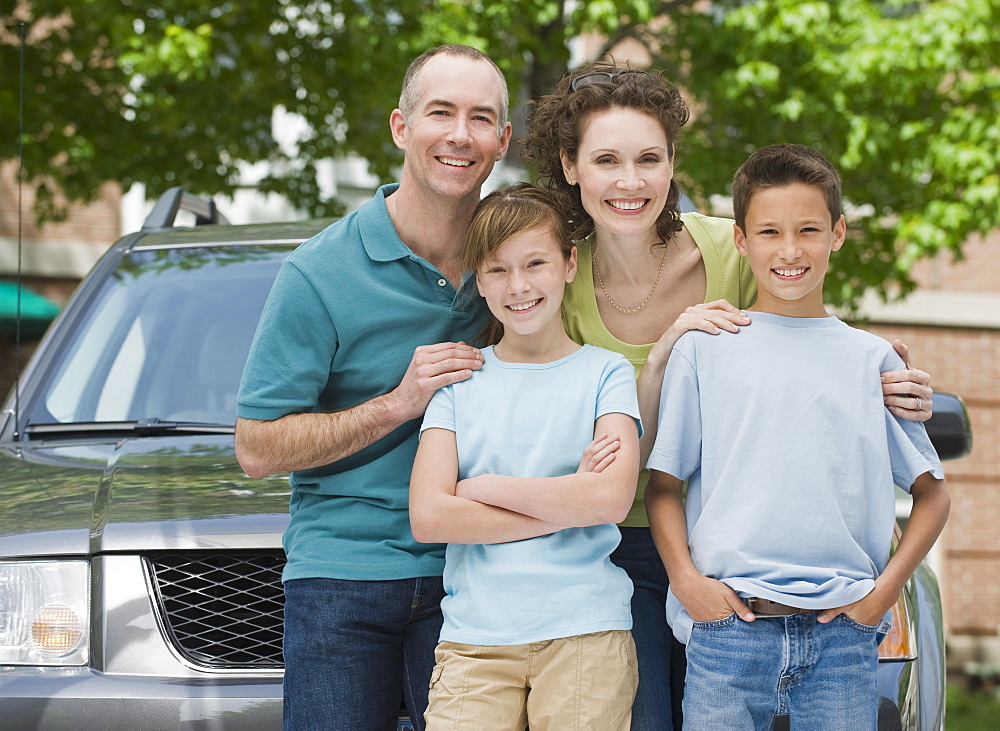 Family with two children in front of car