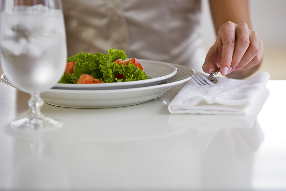 Woman lifting fork next to plate of food