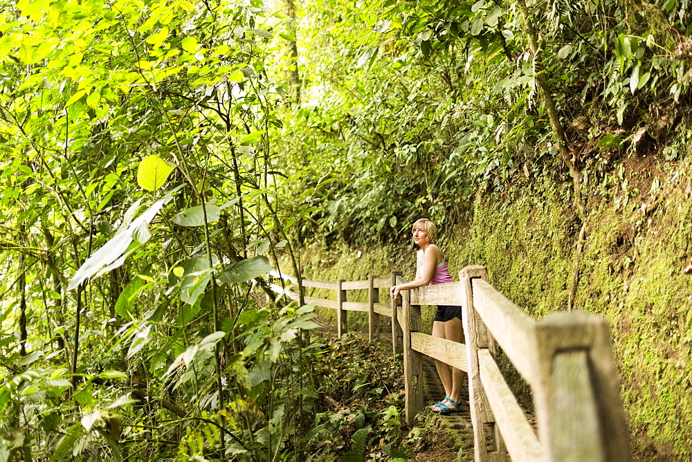 Woman in forest leaning against wooden fence, Costa Rica