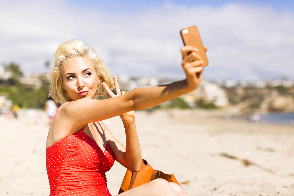 Blond woman taking selfie on beach, Costa Mesa, California
