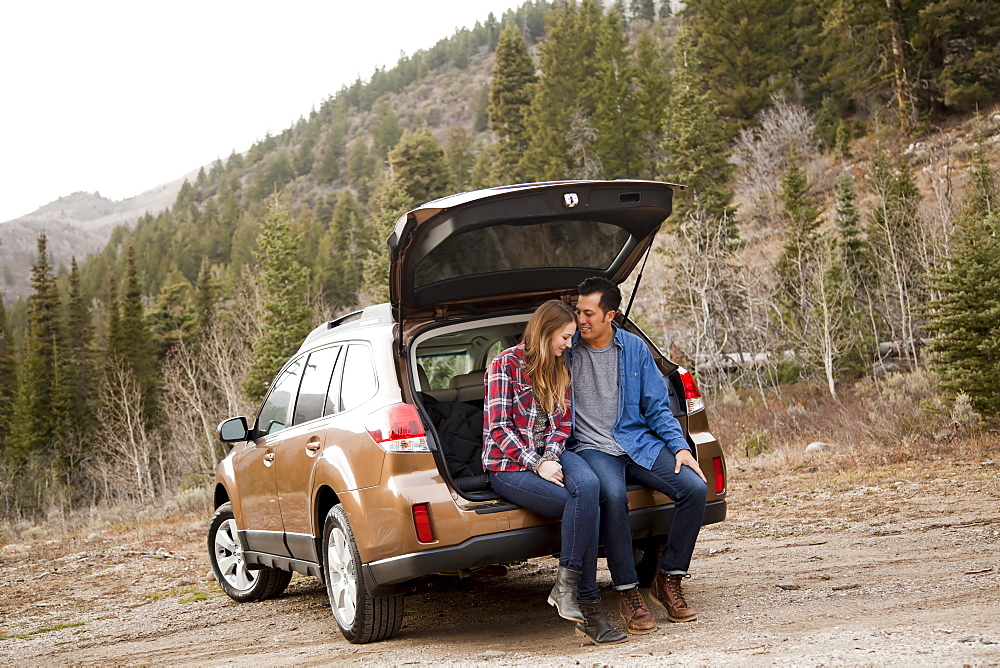 Portrait of young couple sitting in car trunk in non-urban scene, Salt Lake City, Utah