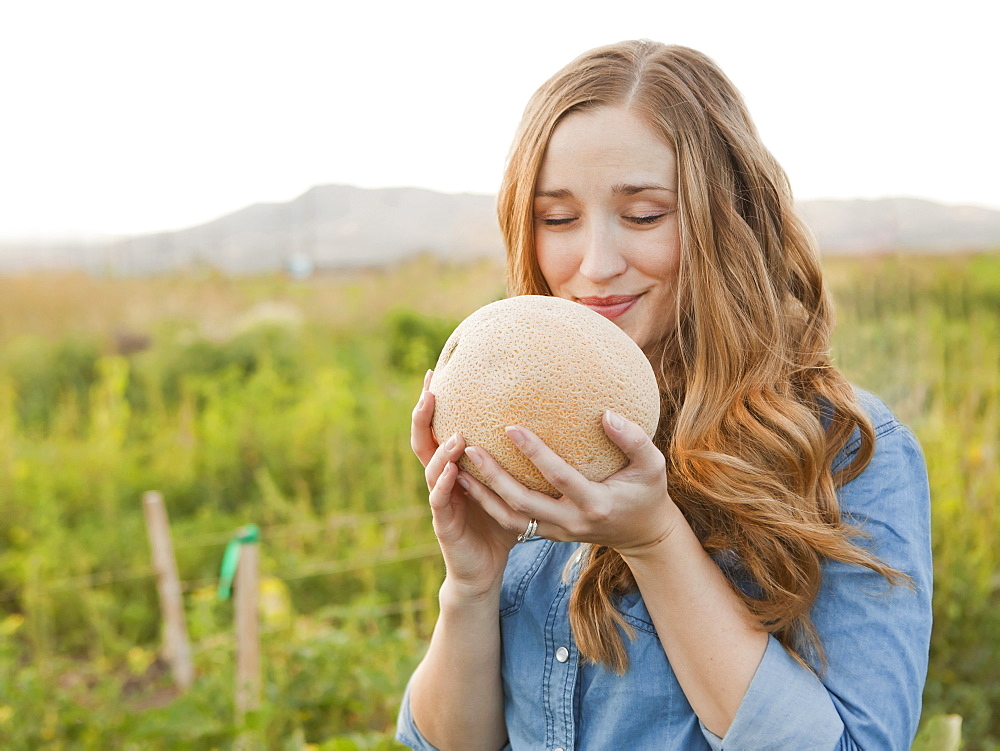 Portrait of young woman holding cantaloupe, Salt Lake City, Utah