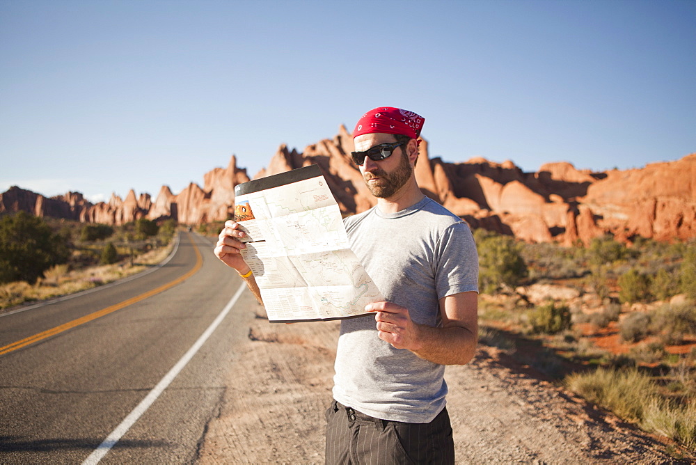 USA, Utah, Moab, Man standing on roadside, reading map, USA, Utah, Moab