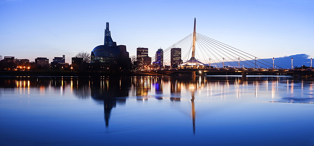 Illuminated skyline reflecting in calm Assiniboine River, Winnipeg Manitoba, Canada