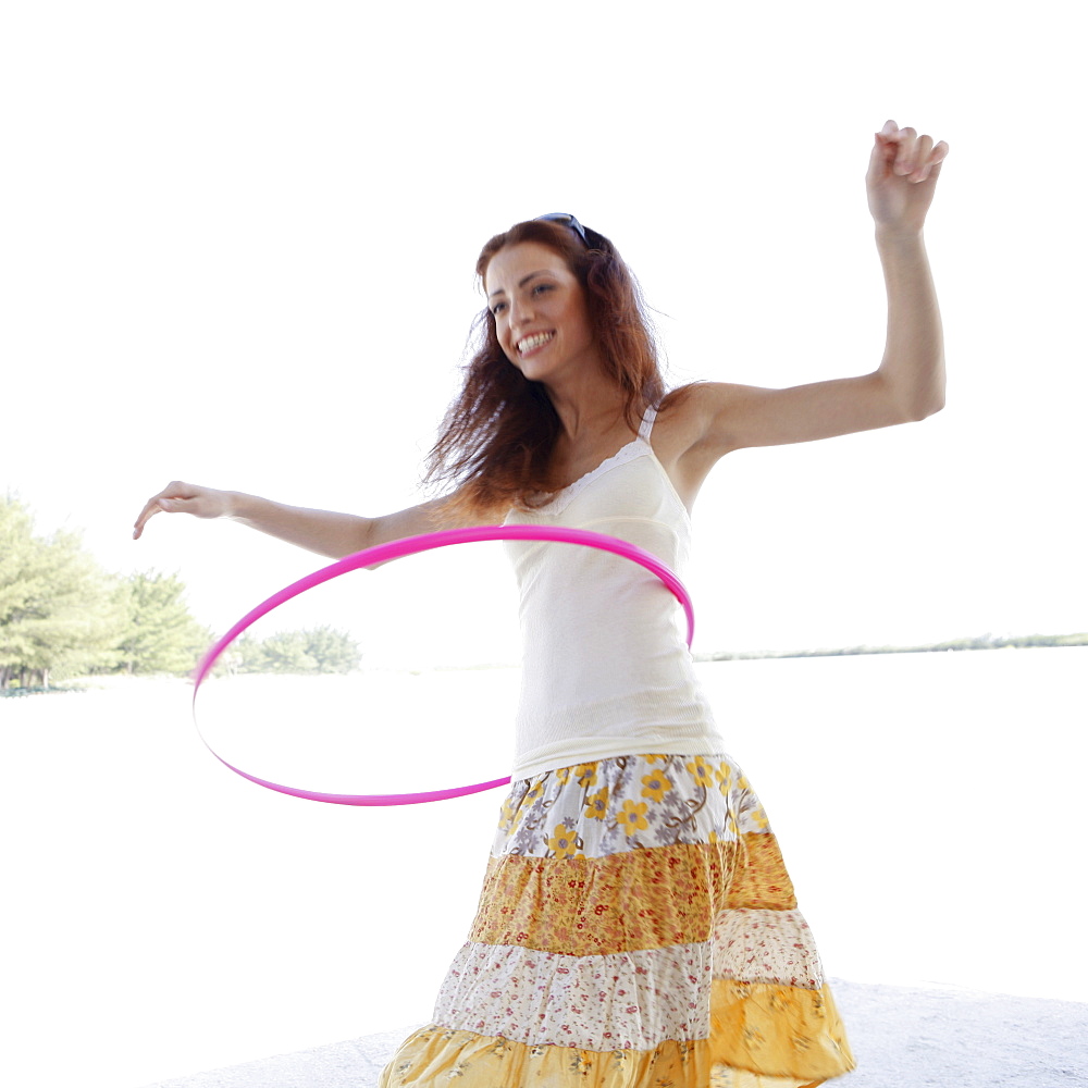 Young woman hula hooping on beach