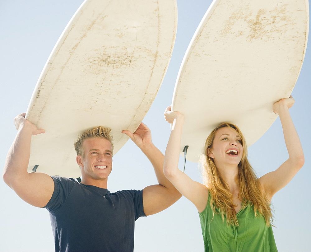 Couple holding surfboards on head