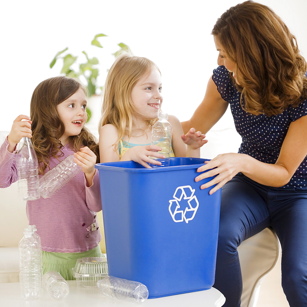 Mother and daughters filling recycling bin