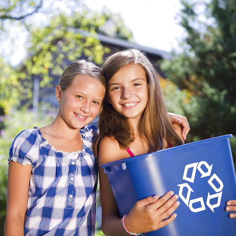 USA, New York, Two girls (10-11, 10-11) holding recycling bin