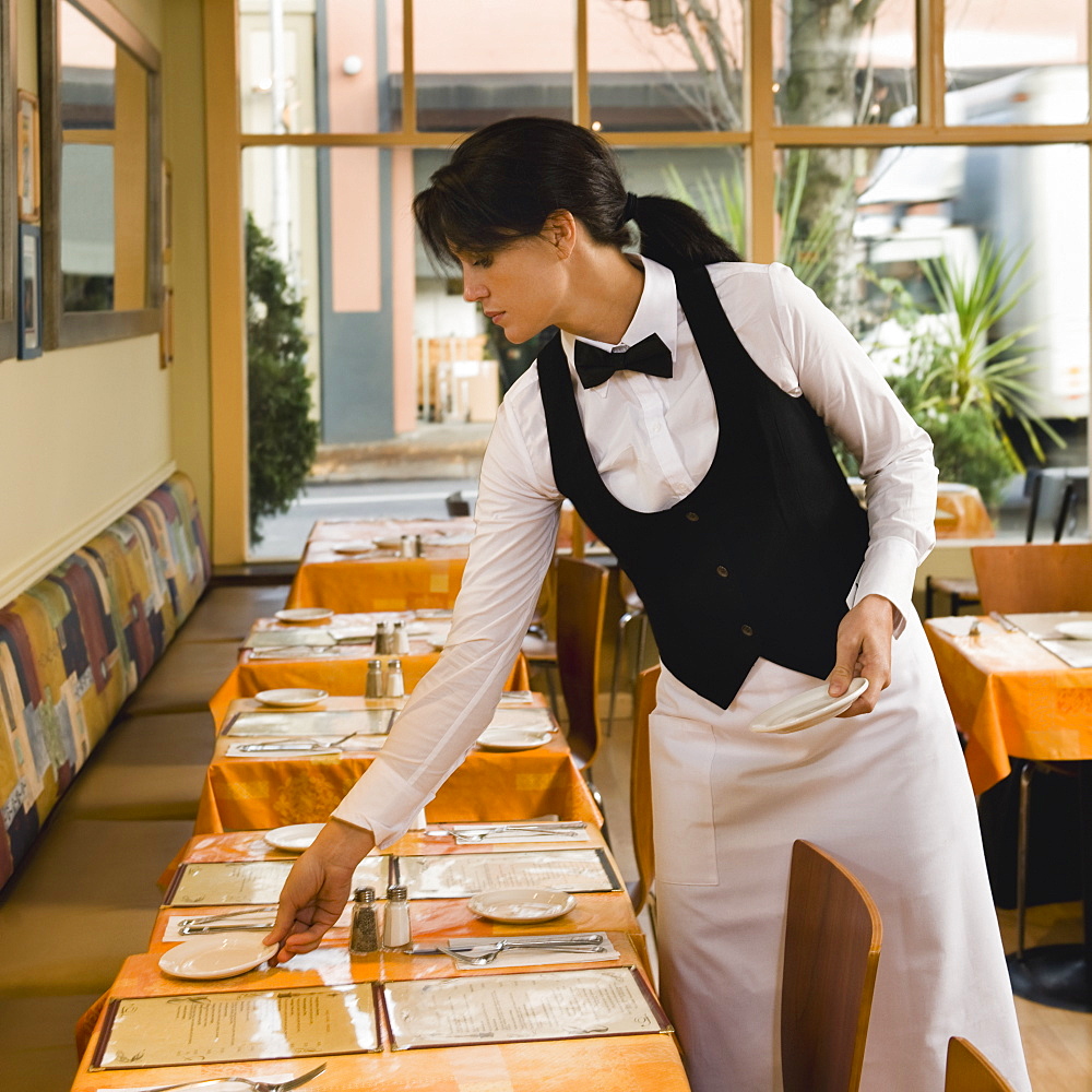 Waitress setting restaurant tables