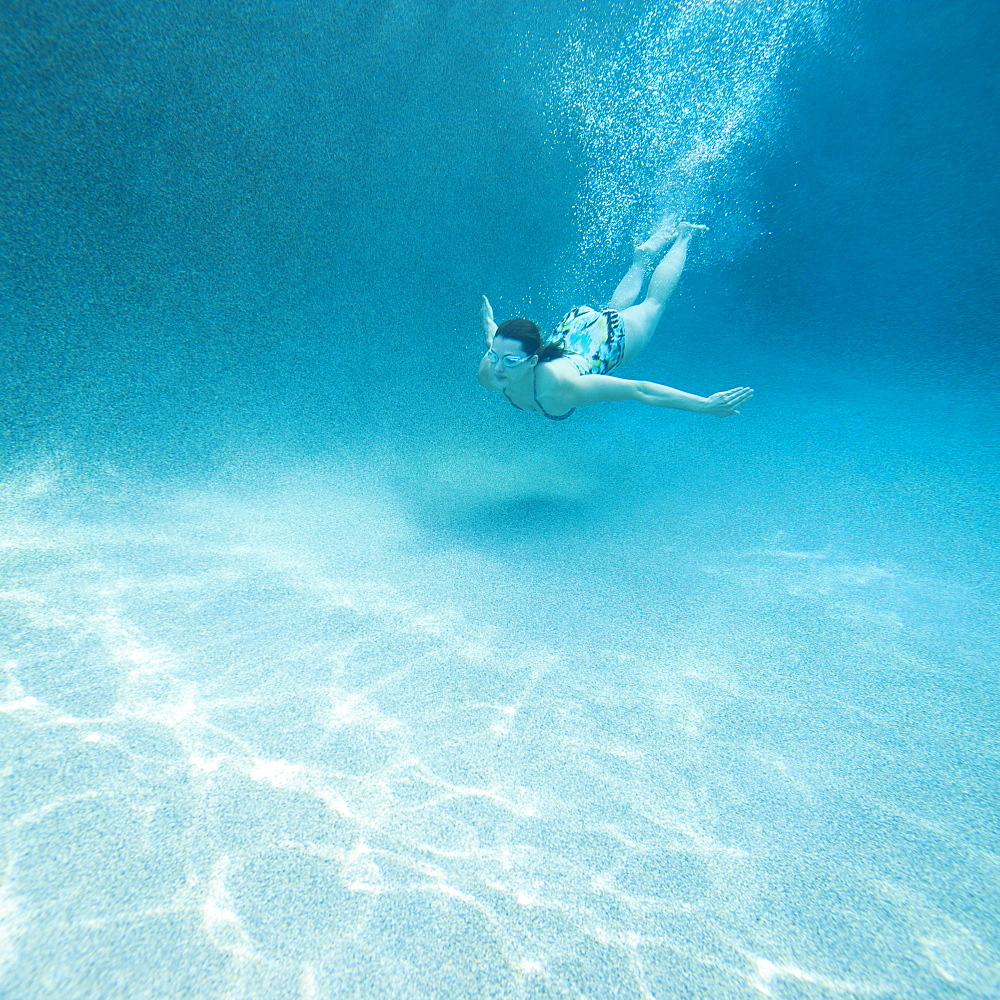 Young attractive woman diving in swimming pool