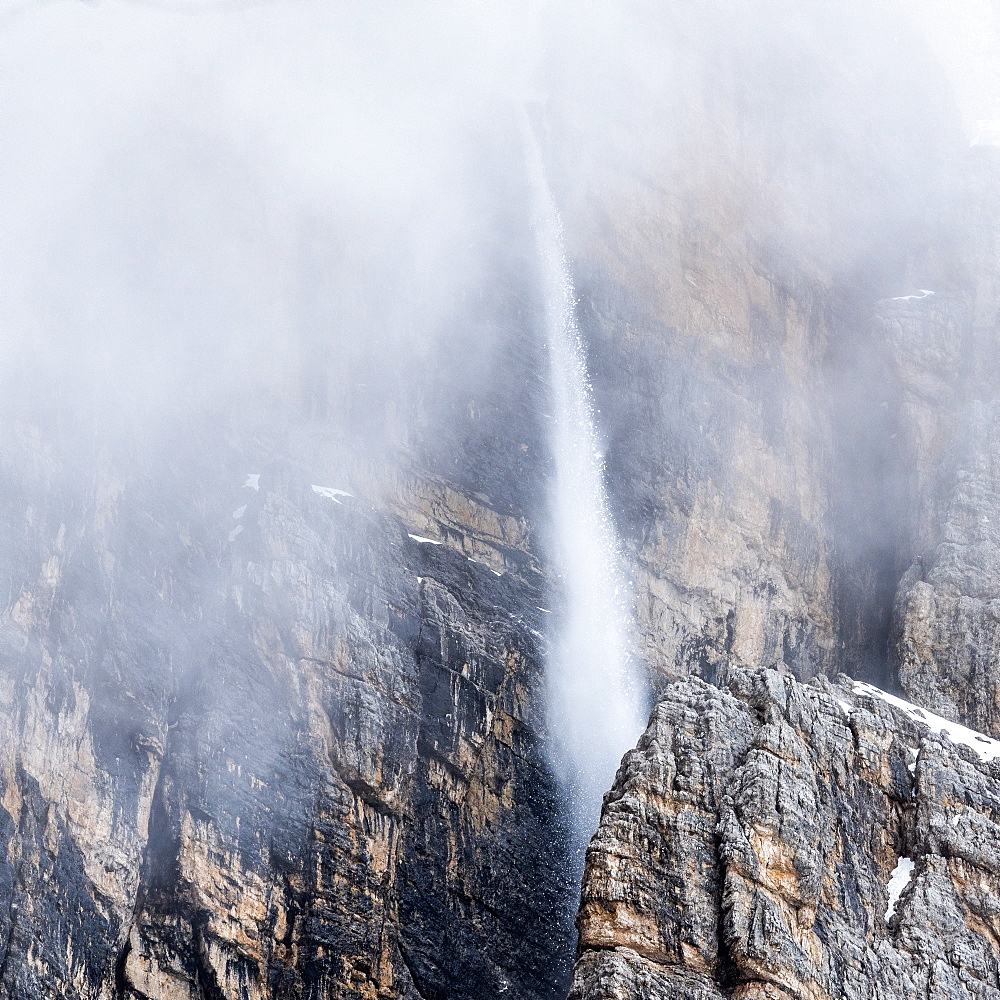 Snow falling down cliff in Dolomites, Passo Giau, Belluno, Italy