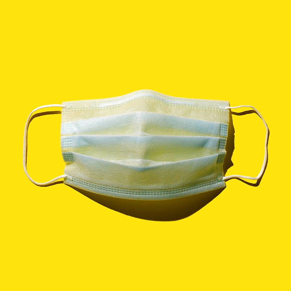 Surgical mask against yellow background