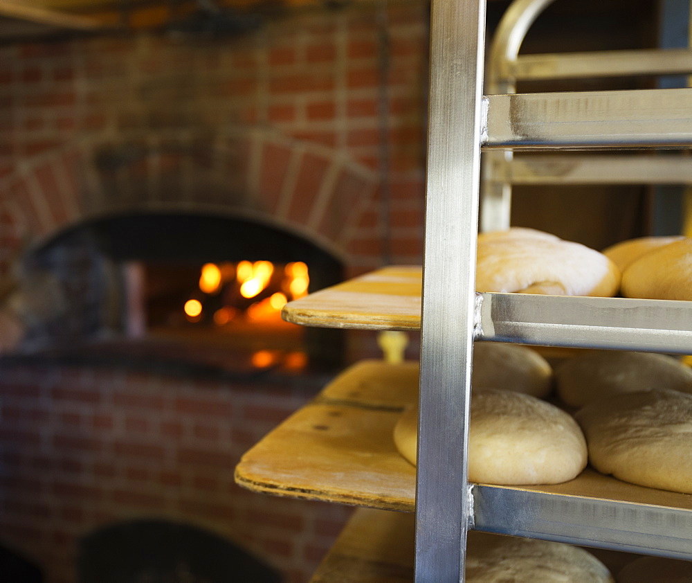 Artisan bread on shelves in kitchen with brick oven