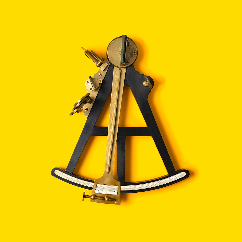 Studio shot of navigational octant against yellow background