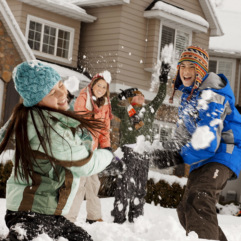 USA, Utah, Provo, Boys (10-11, 12-13) and girls (10-11, 16-17) having snow ball fight in front of house