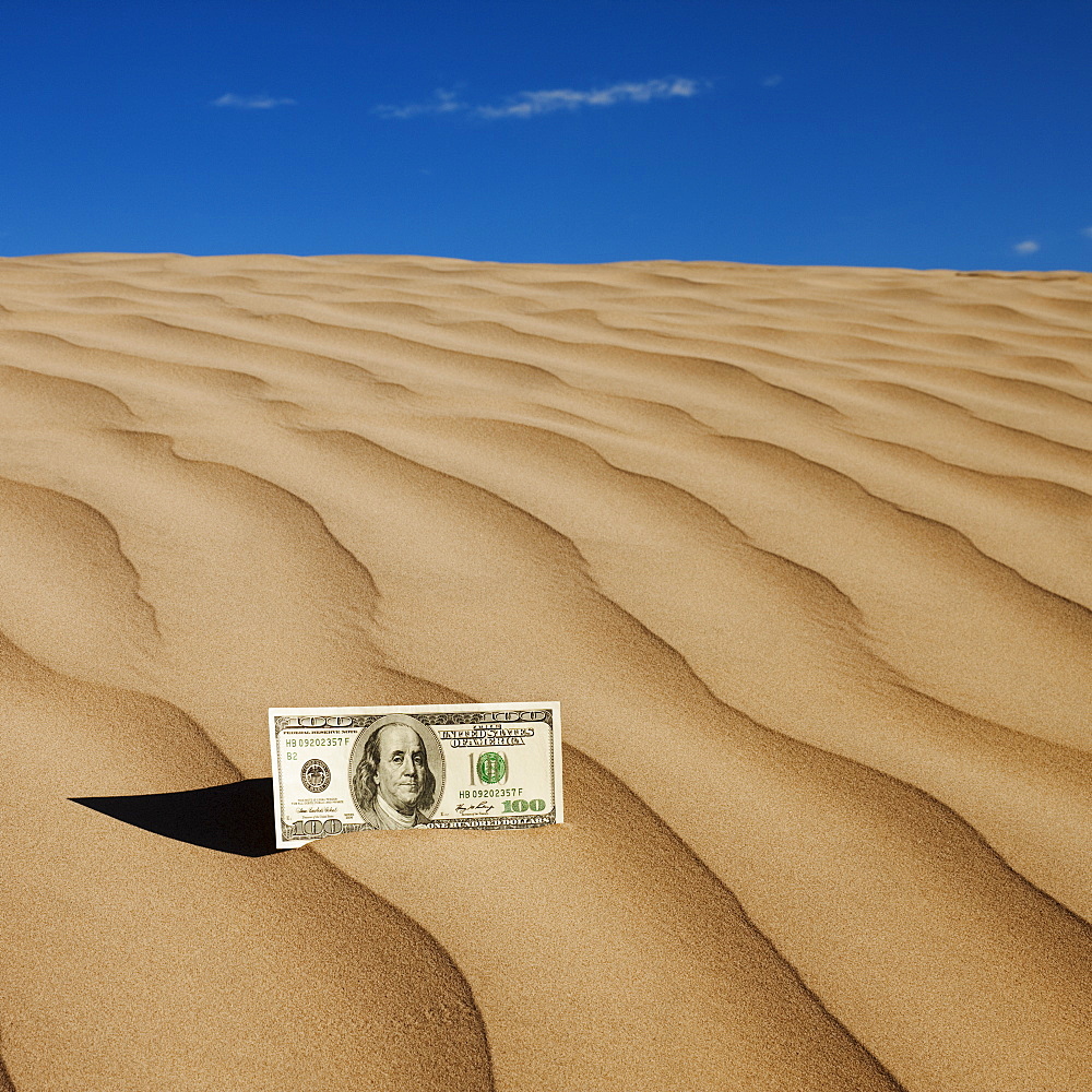 100 dollar bill on sand in desert