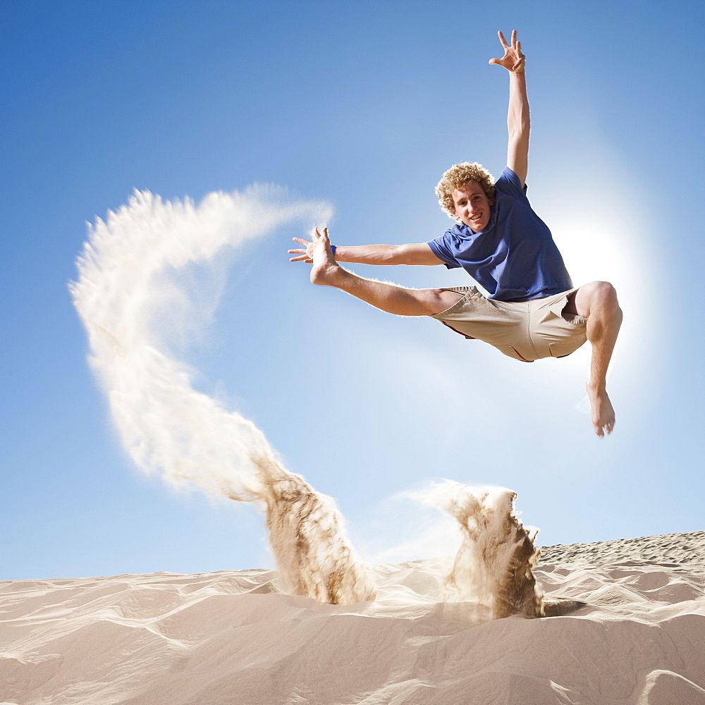 Energetic man jumping in the sand