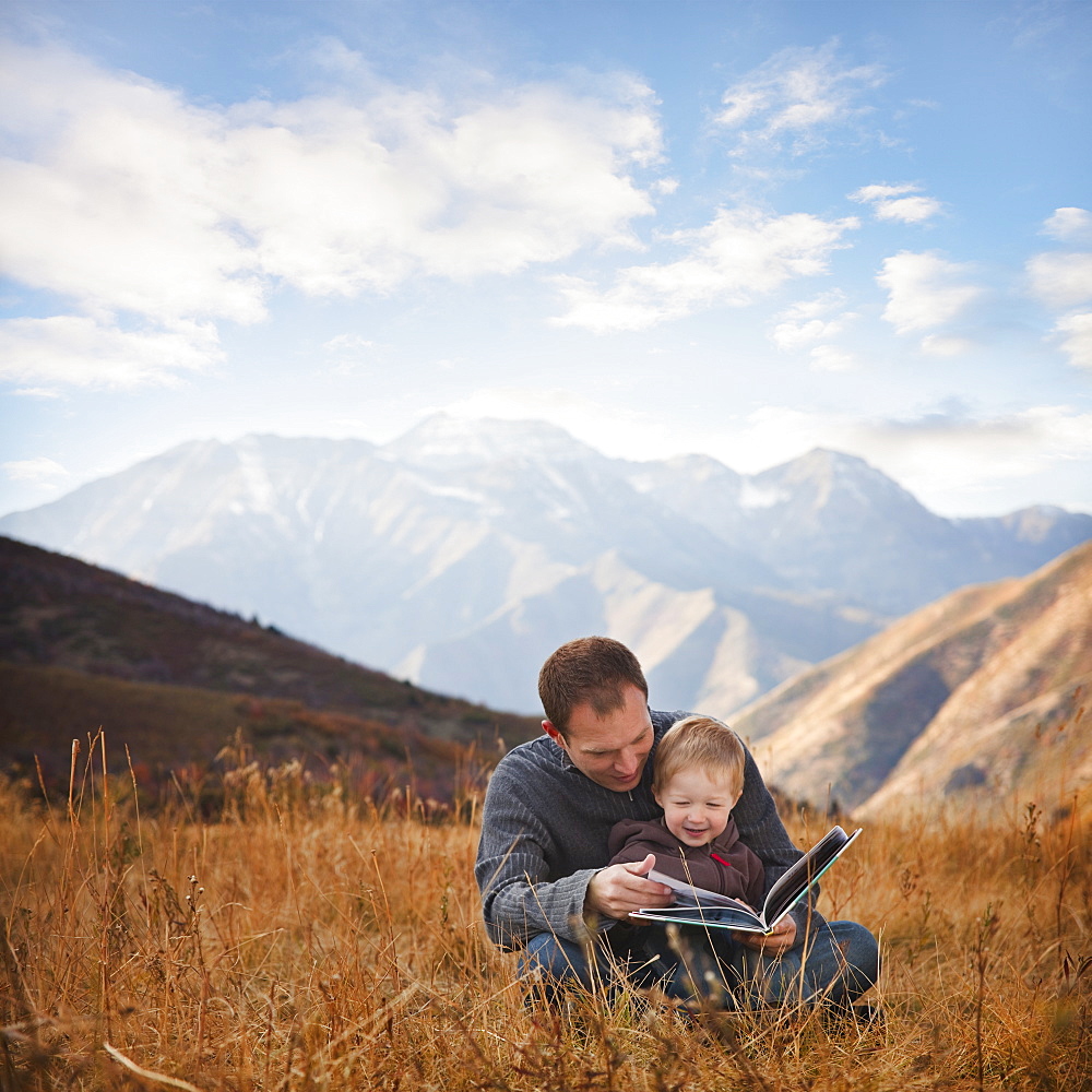 Father and son reading outdoors