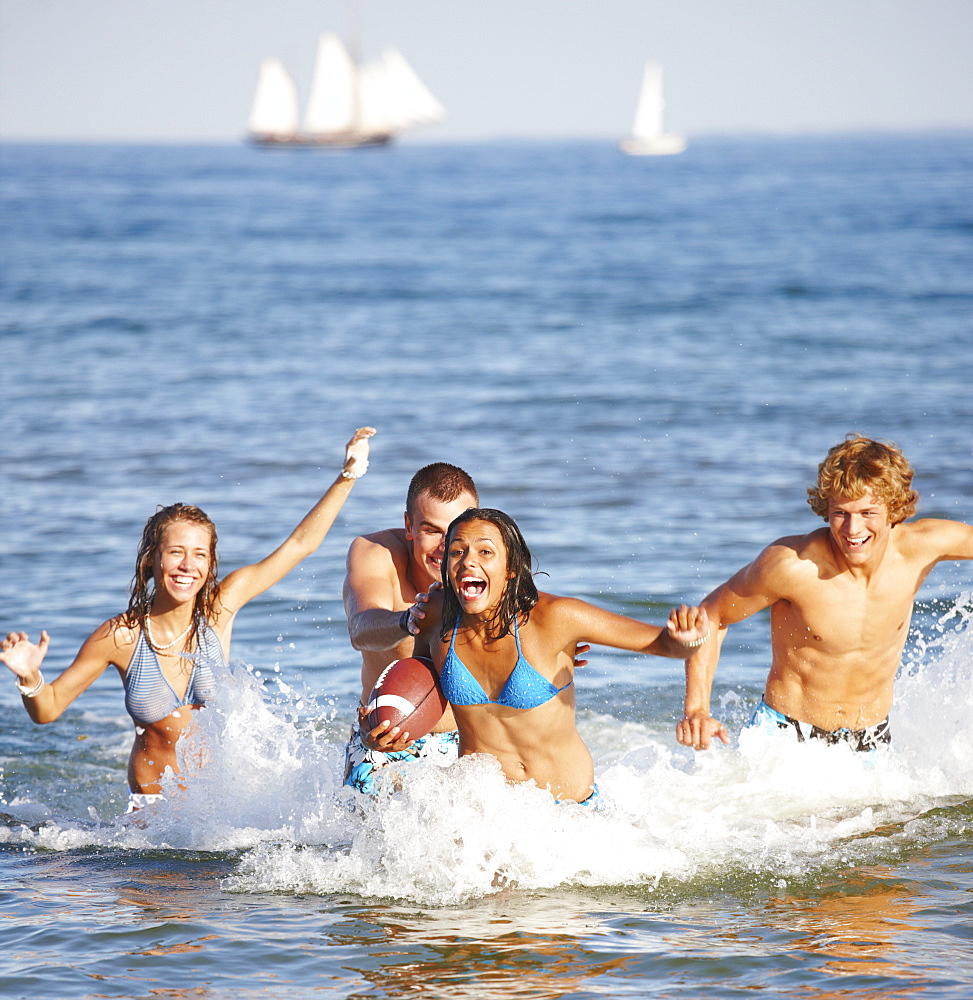 Young friends playing football in ocean