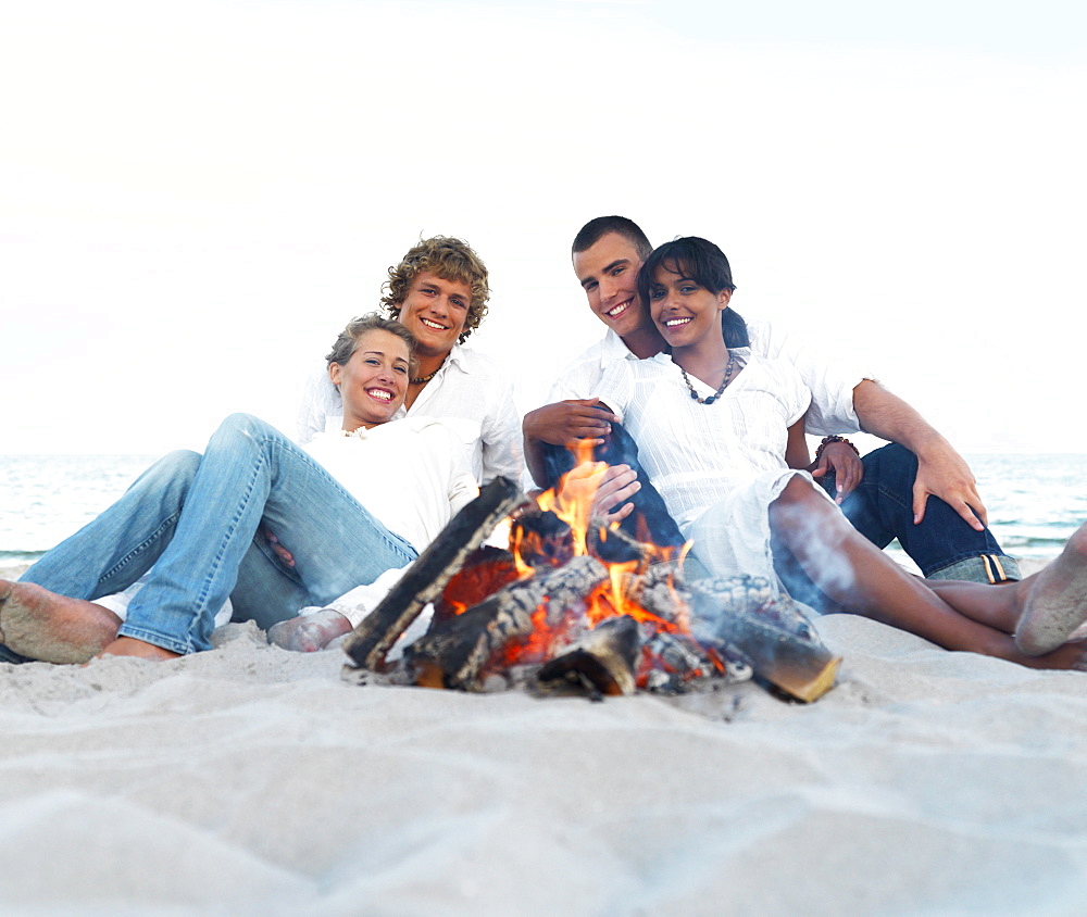 Young couples hugging by campfire on beach