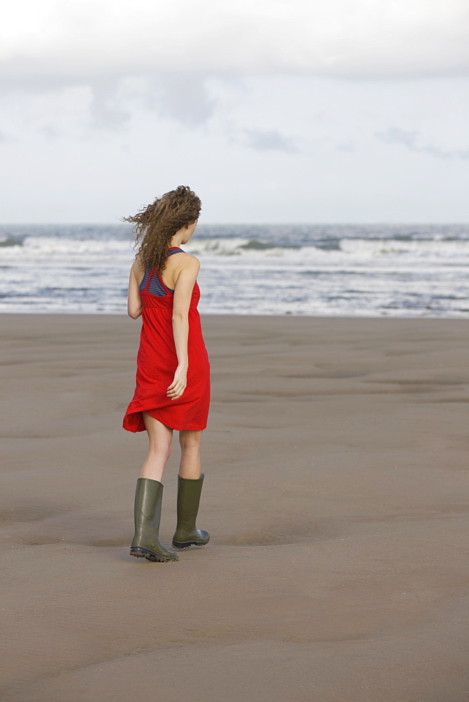 France, Pas-de-Calais, Escalles, Young woman strolling on empty beach, France, Pas-de-Calais, Escalles