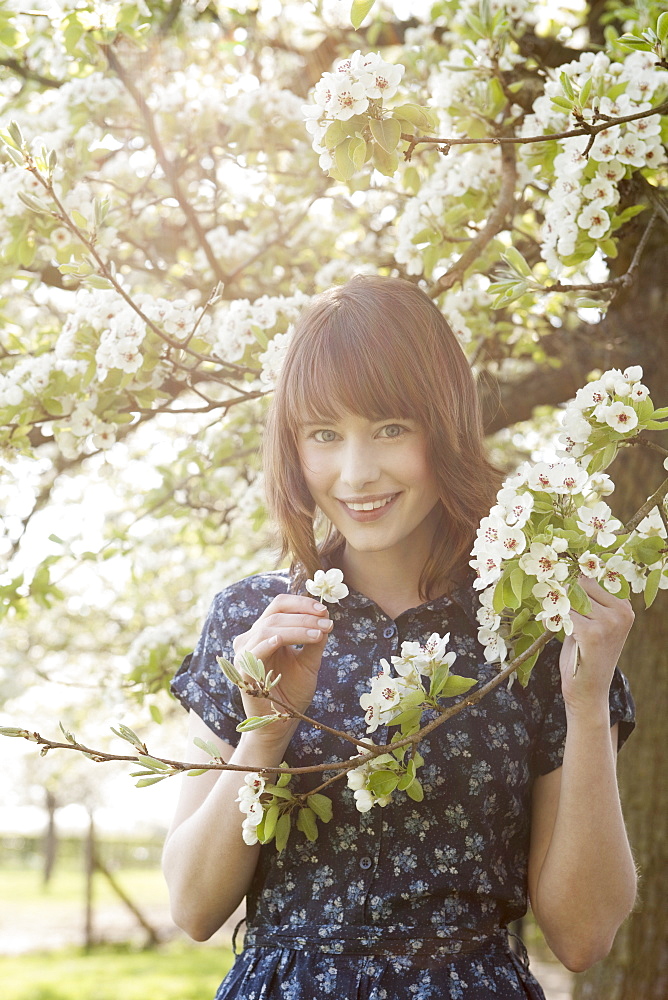 Portrait of young woman in blooming orchard