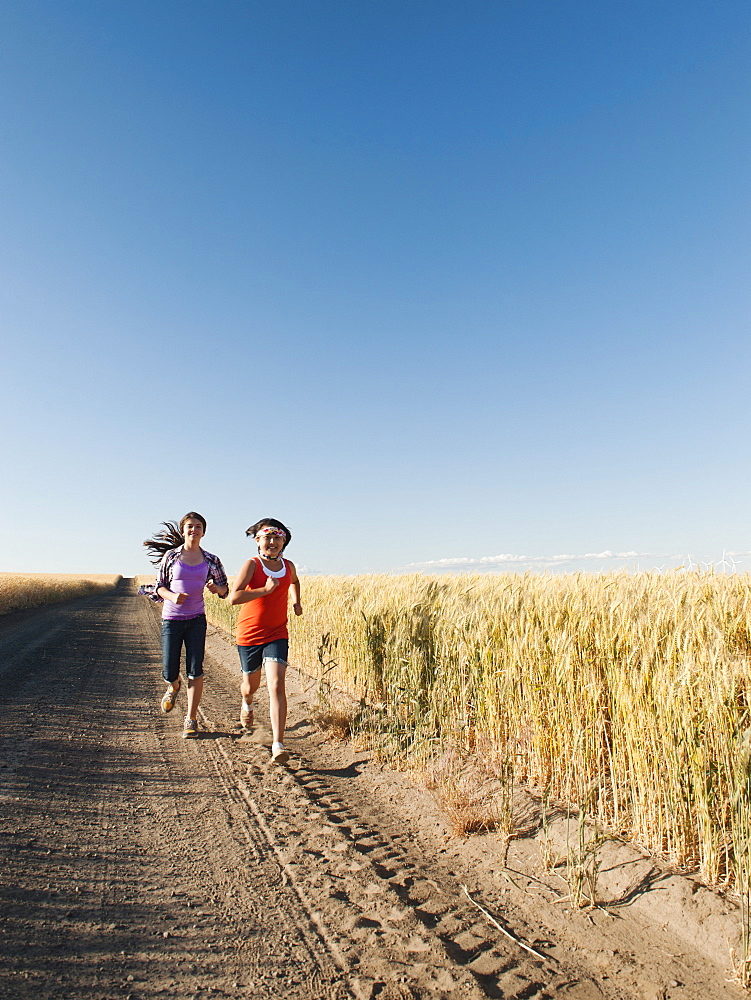 Girls (12-13, 10-11) running along dirt road