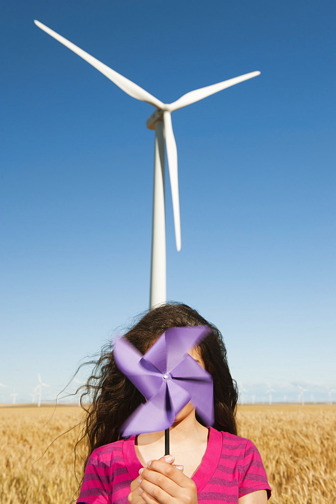 USA, Oregon, Wasco, Girl (12-13) holding fan n front of wind turbines