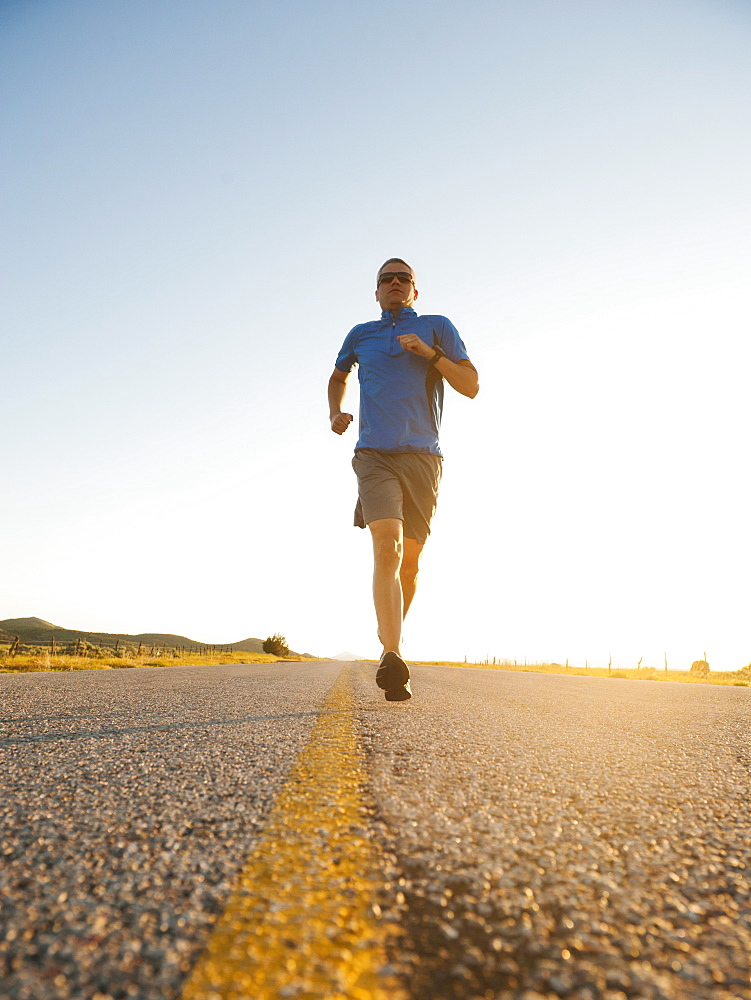 Mid adult couple running on empty road